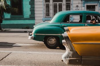 VINTAGE CAR ON ROAD BY BUILDINGS