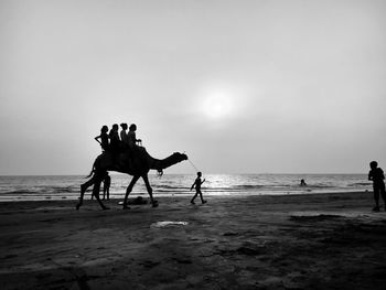 Silhouette people on beach against sky