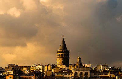 Buildings in city against cloudy sky