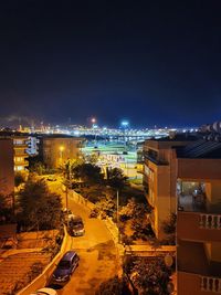 High angle view of illuminated street amidst buildings in city at night