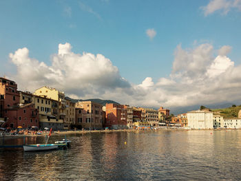 Buildings by river against sky in city