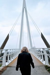 Rear view of woman standing on bridge against sky