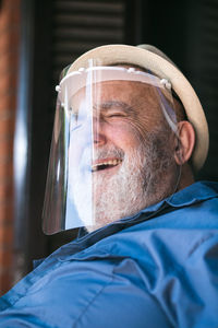 Elderly man smiling under a protective visor