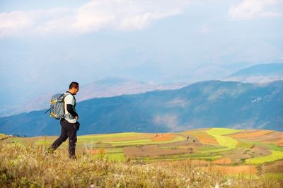 Man standing on field against mountain range