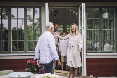 Happy woman greeting father while standing near doorway