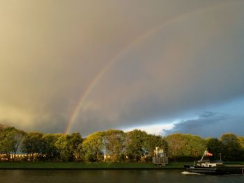 Scenic view of rainbow over lake against sky