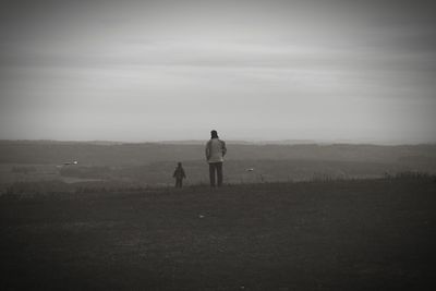 Rear view of couple standing on field against sky