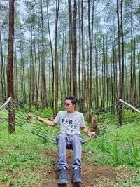 Young man sitting on tree trunk in forest