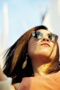 Low angle view of woman wearing sunglasses looking away while standing outdoors