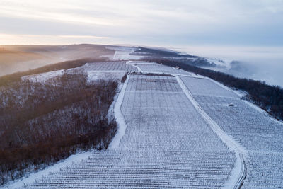 Road leading towards snow covered landscape against sky