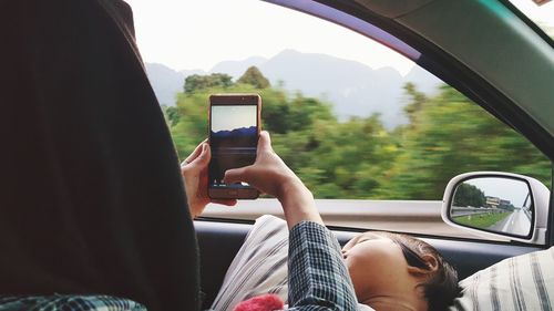 Woman using mobile phone while sitting with baby in car