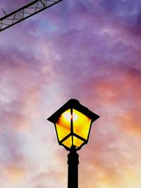 Low angle view of illuminated street light against cloudy sky