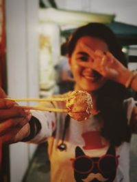 Close-up of smiling woman holding meatballs with chopsticks