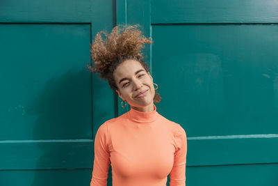 Smiling woman standing against green door