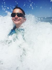 Cheerful boy wearing sunglasses enjoying in sea waves