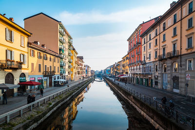 Canal amidst buildings in city against sky