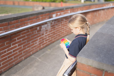 Side view of girl holding toy while leaning on railing