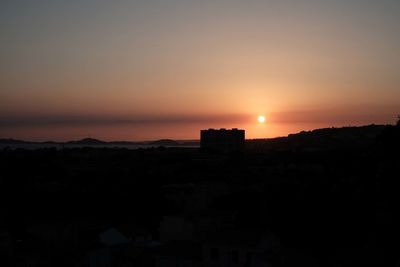 Silhouette buildings against sky during sunset