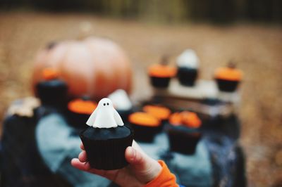 Cropped hand of child holding cupcake during halloween celebration