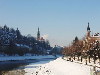 Buildings in city against clear sky during winter