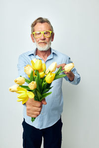 Portrait of young man holding flower against white background