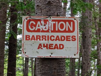 Caution barricades ahead sign attached to a tree in the forest 
