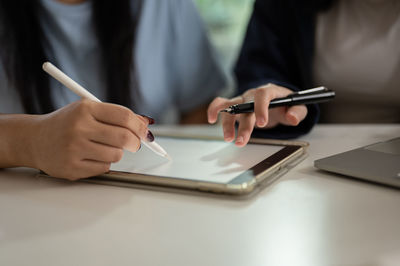 Midsection of man using mobile phone on table