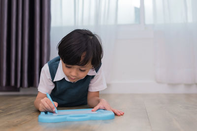 Cute boy writing on slate at home