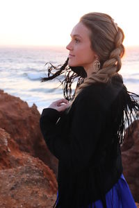 Side view of woman standing at beach against sky