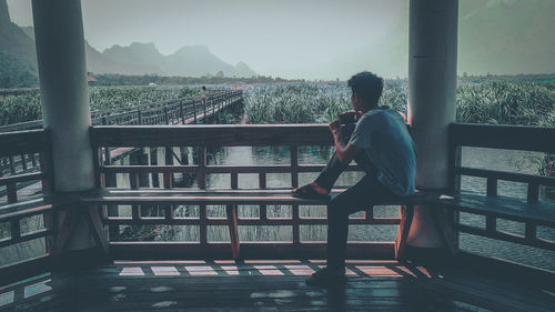 Side view of man looking at landscape while sitting in gazebo