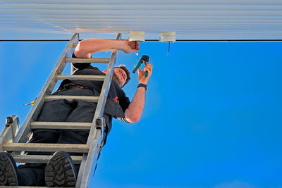 Low angle view of clothes hanging against clear blue sky