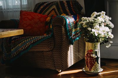 Chair by white flowers in vase at home