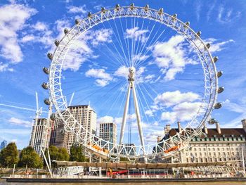 Low angle view of ferris wheel against cloudy sky