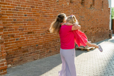 Full length of woman standing against brick wall