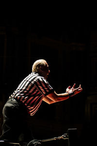 Side view of man sitting on stage