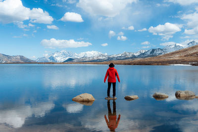 Rear view of man standing in lake against sky