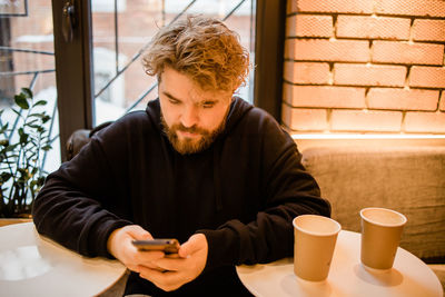 Young man using mobile phone while sitting on table