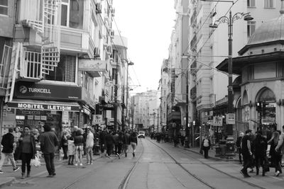 People walking on street amidst buildings in city