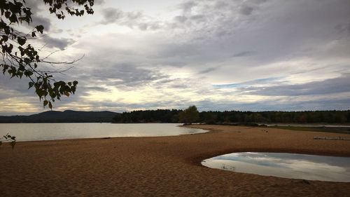 View of calm lake against cloudy sky