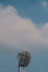 Low angle view of communications tower against cloudy sky