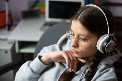 A young brunette girl focused on listening to music on wireless headphones.