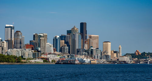 Sea by buildings against blue sky