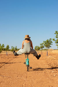 Rear view of woman riding motorcycle on field against clear sky