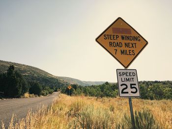 Road sign on field against clear sky