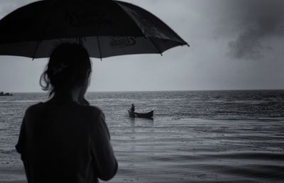 Rear view of woman under umbrella at beach