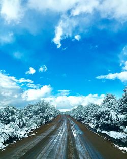 Road amidst snow covered trees against sky