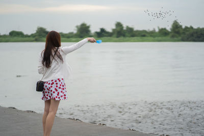 Rear view of woman standing against sea