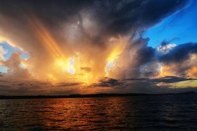 Scenic view of sea against dramatic sky during sunset