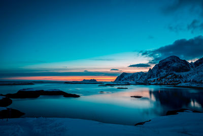 Scenic view of sea and snowcapped mountains against sky at sunset