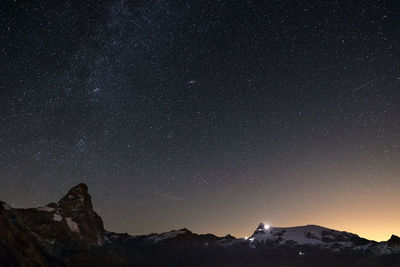 Low angle view of stars against mountains at night